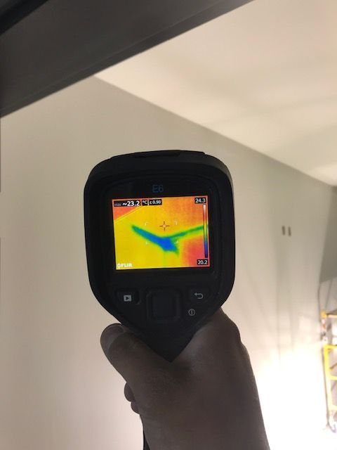 Un homme en combinaison de protection pulvérise une pièce avec un pulvérisateur.
