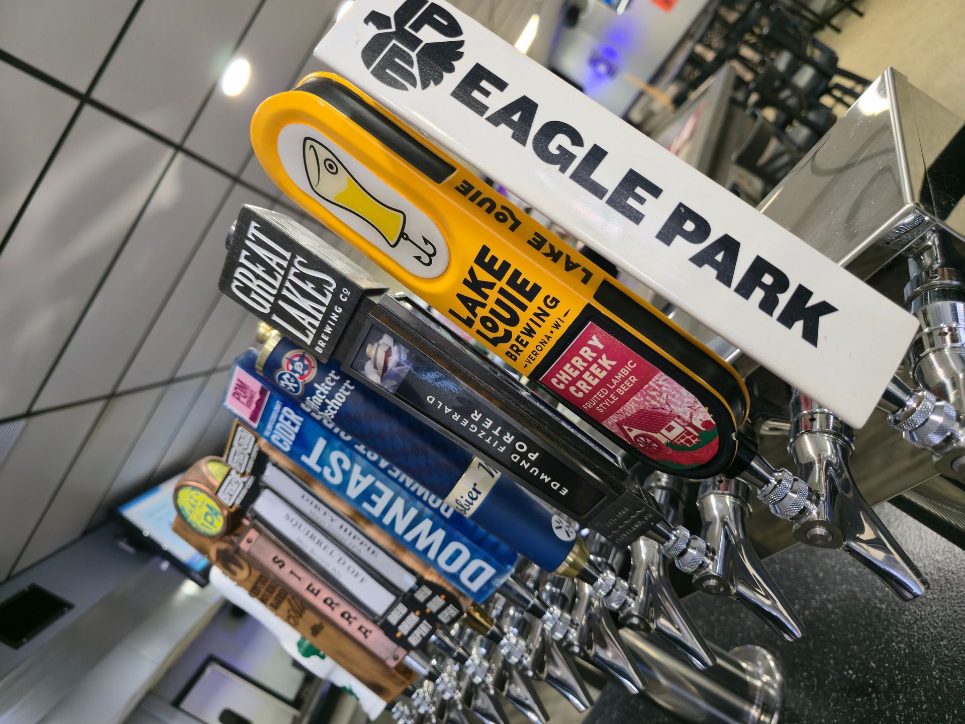 A line of beer tap handles from various breweries, including Eagle Park, Lake Louie, Great Lakes, and Downeast.