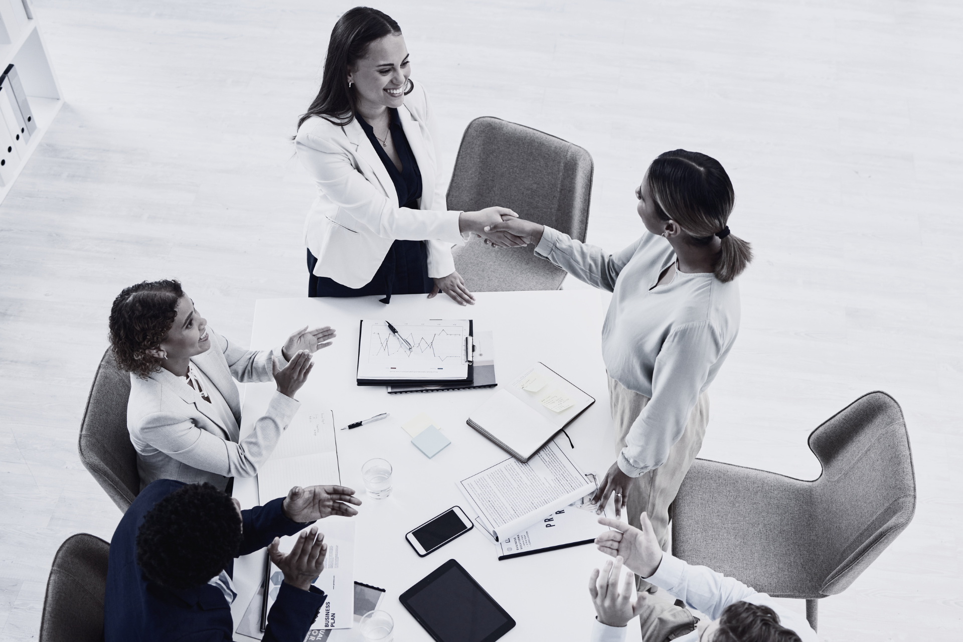 A group of people are sitting around a table shaking hands.