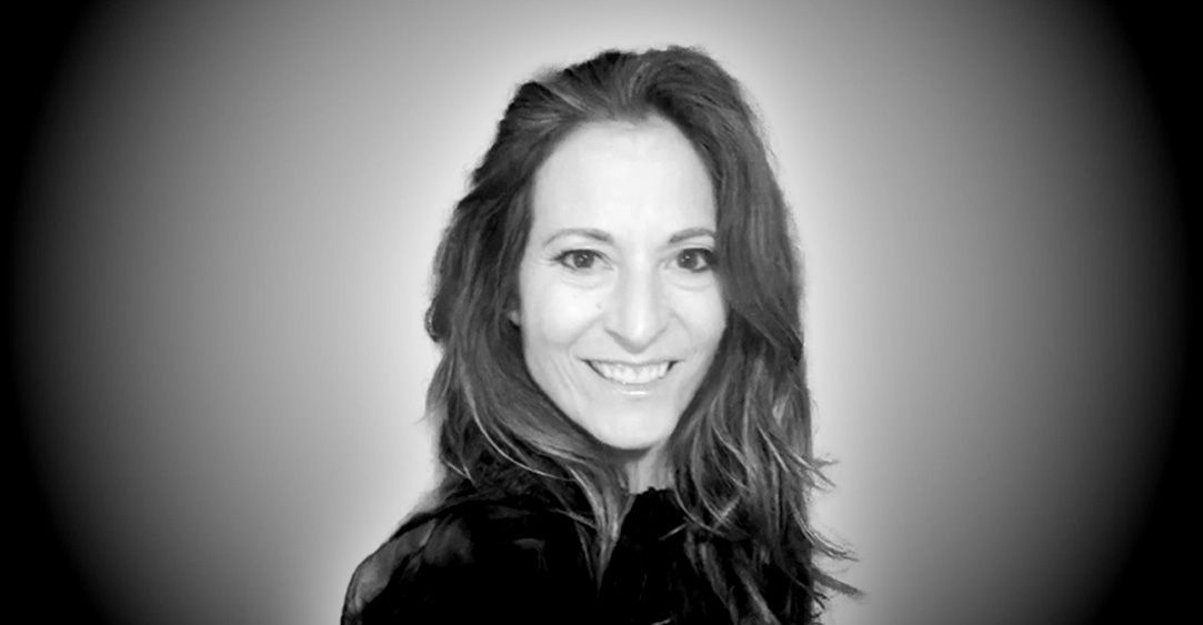 A woman with long hair is smiling in a black and white photo.