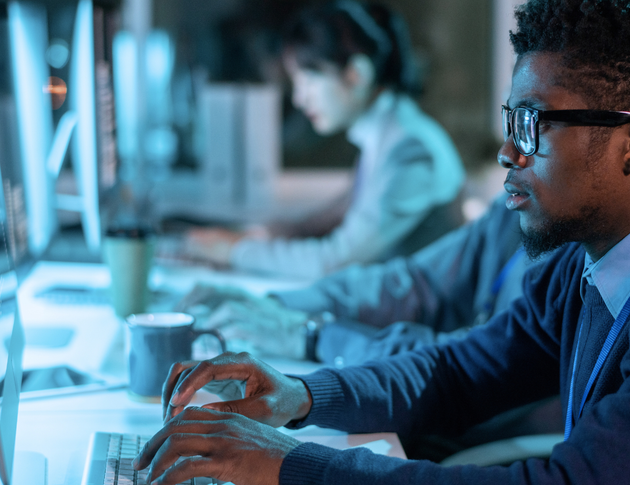 A man wearing glasses is typing on a computer keyboard