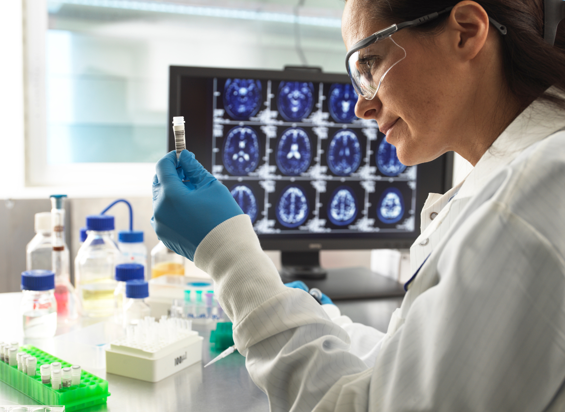 A woman in a lab coat is looking at a test tube