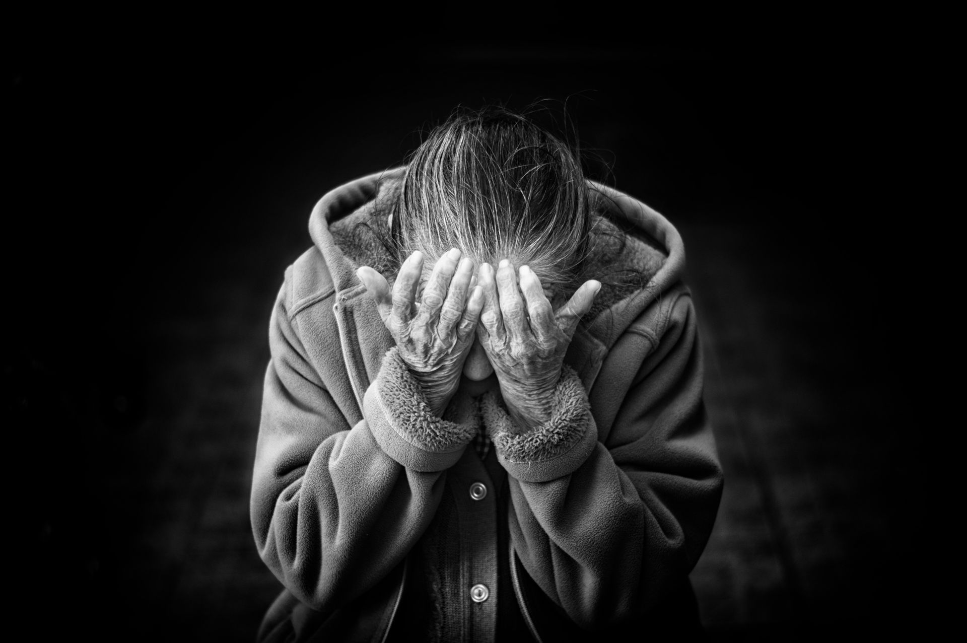 A woman is covering her face with her hands in a black and white photo.