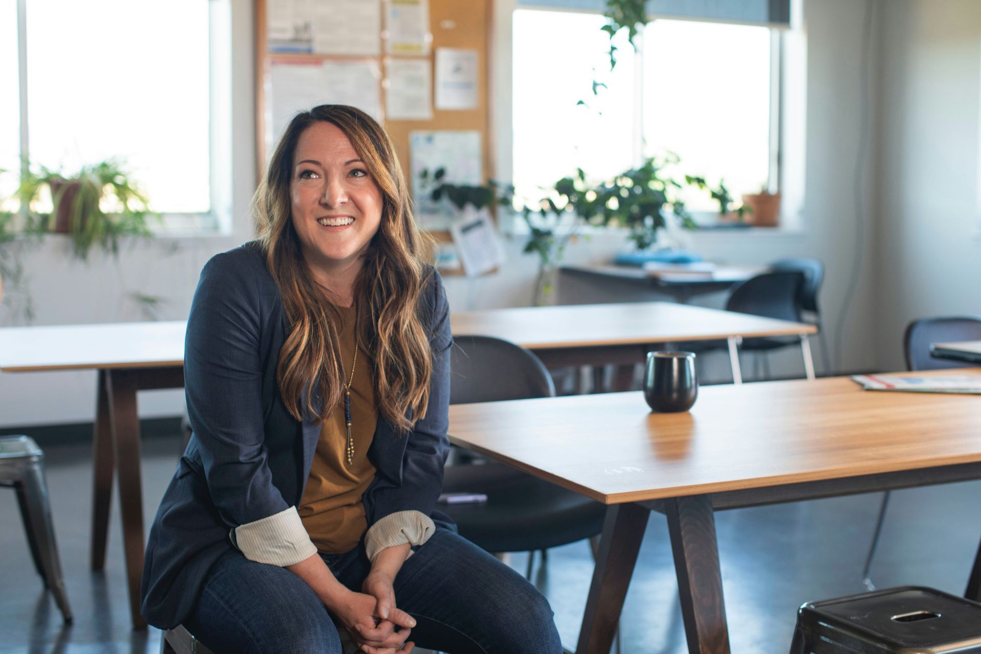 A woman is sitting at a table in a classroom.