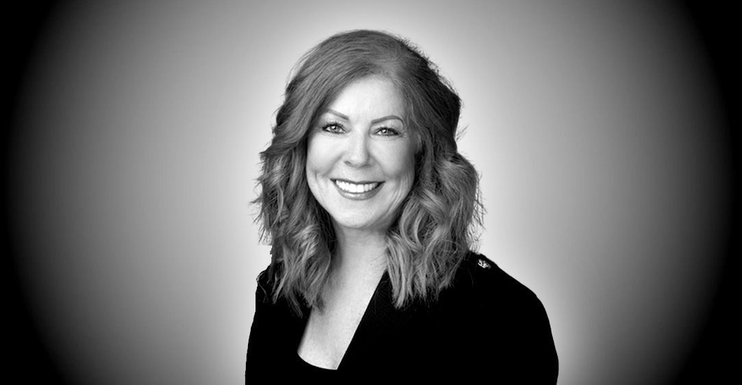 A woman with red hair is smiling in a black and white photo.