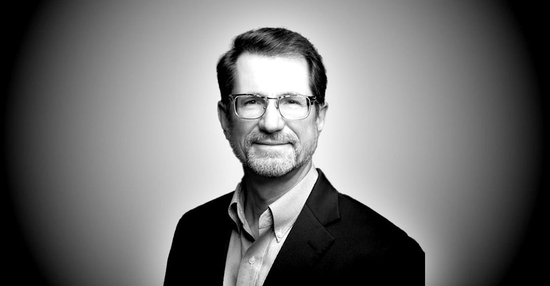 A black and white photo of a man wearing glasses and a suit.