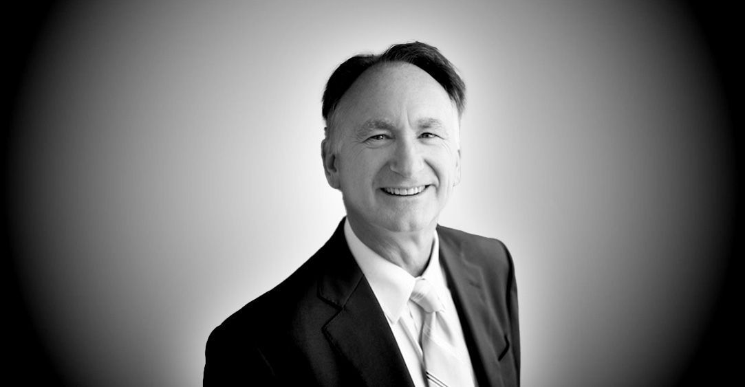 A man in a suit and tie is smiling in a black and white photo.