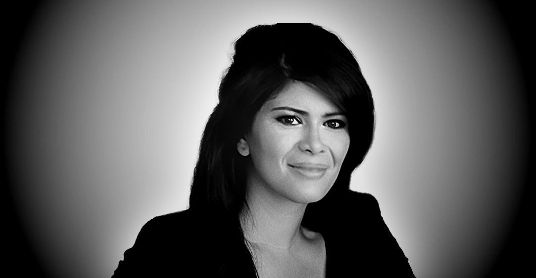 A woman with long hair is smiling in a black and white photo.