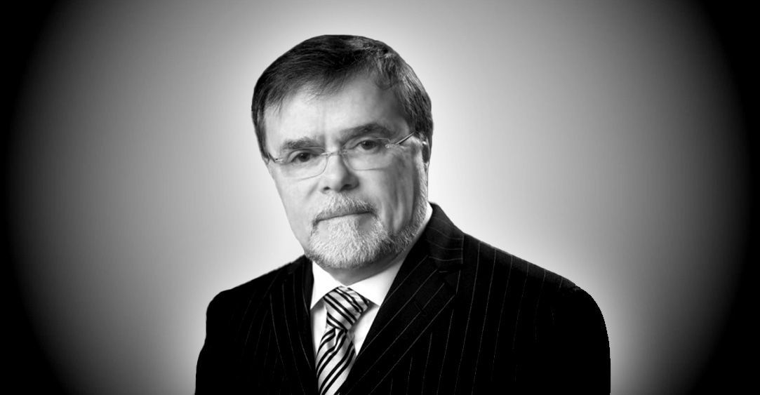 A man with a beard and glasses is wearing a suit and tie.