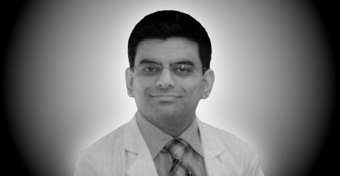 A black and white photo of a man in a lab coat and tie.