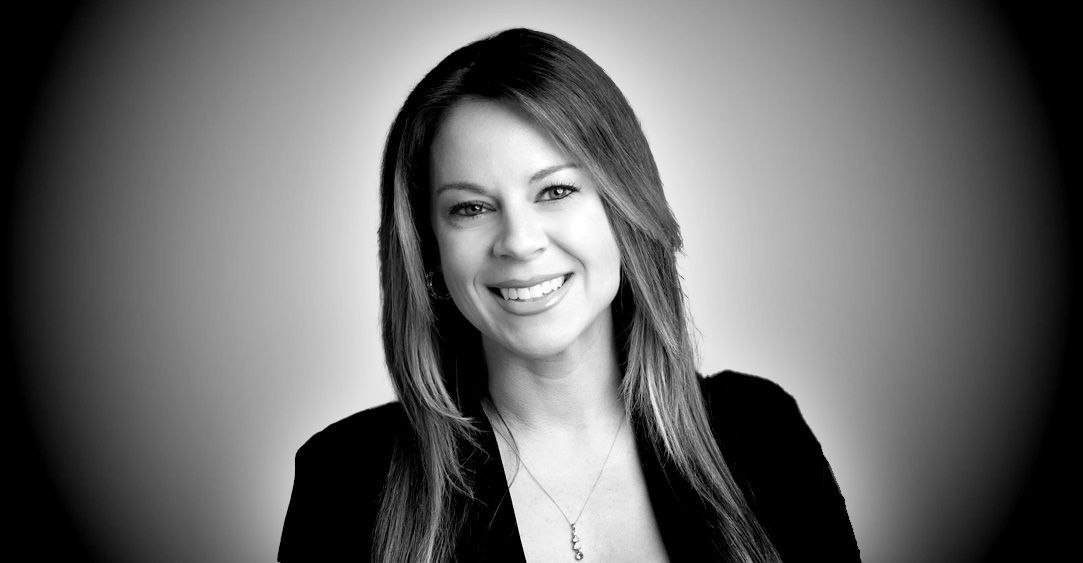 A woman with long hair is smiling in a black and white photo.