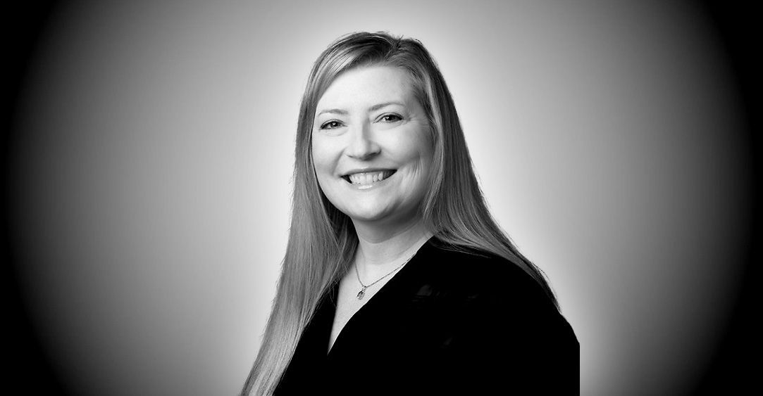 A woman with long hair is smiling in a black and white photo.