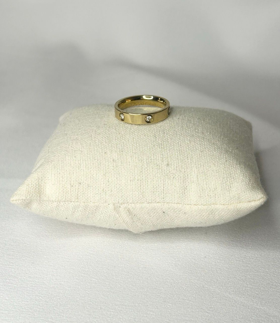 Une bague en or est posée sur un oreiller blanc.