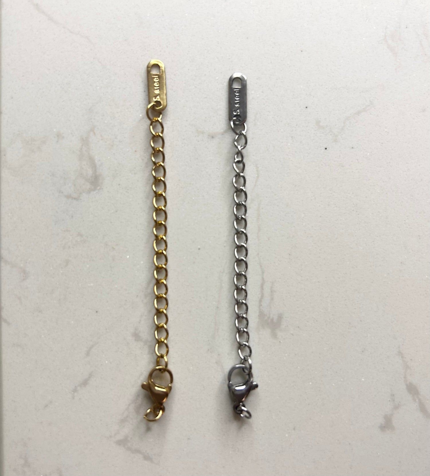Une chaîne en or et une chaîne en argent sur une surface blanche