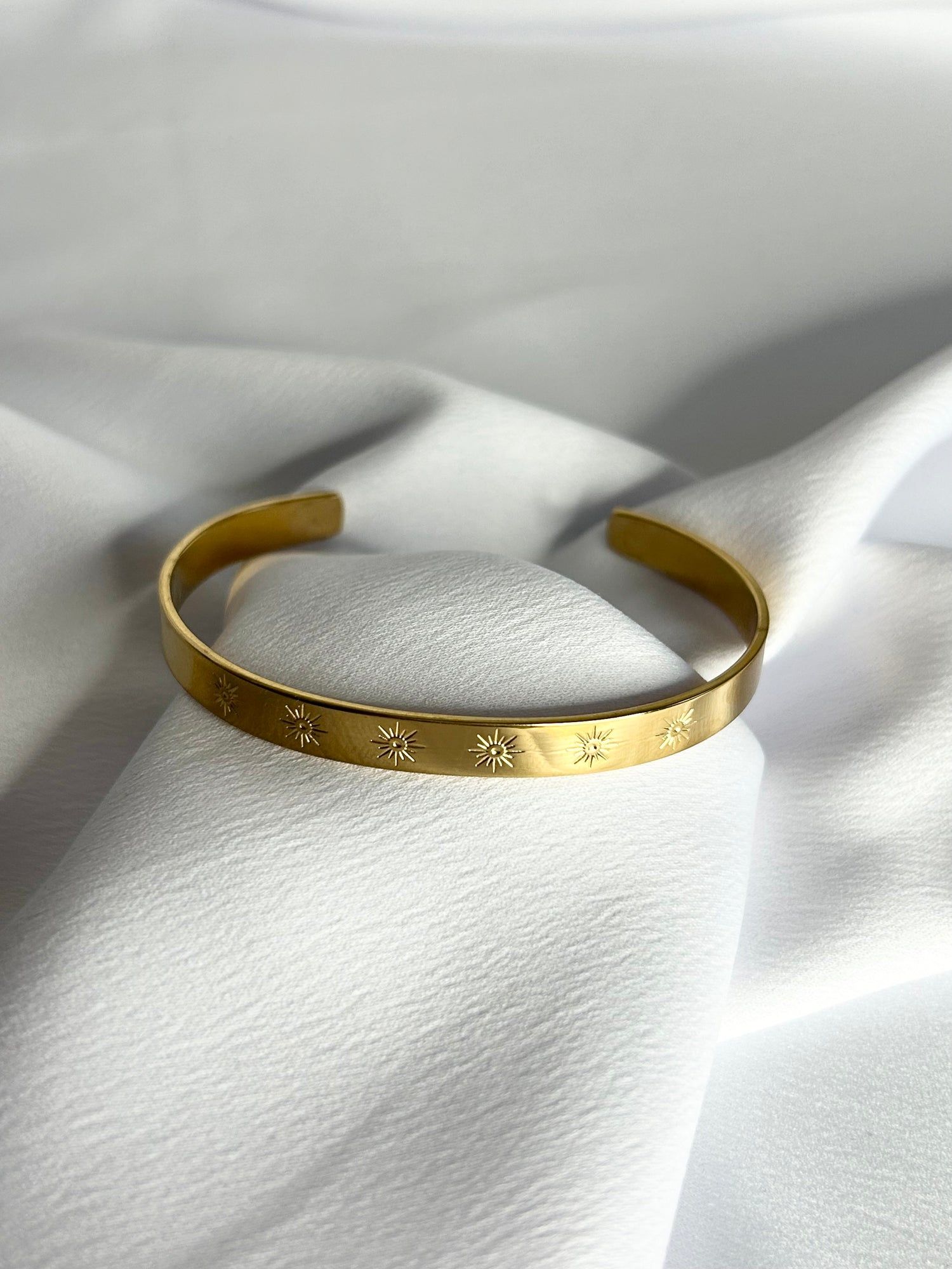 Un bracelet en or est posé sur un tissu blanc.