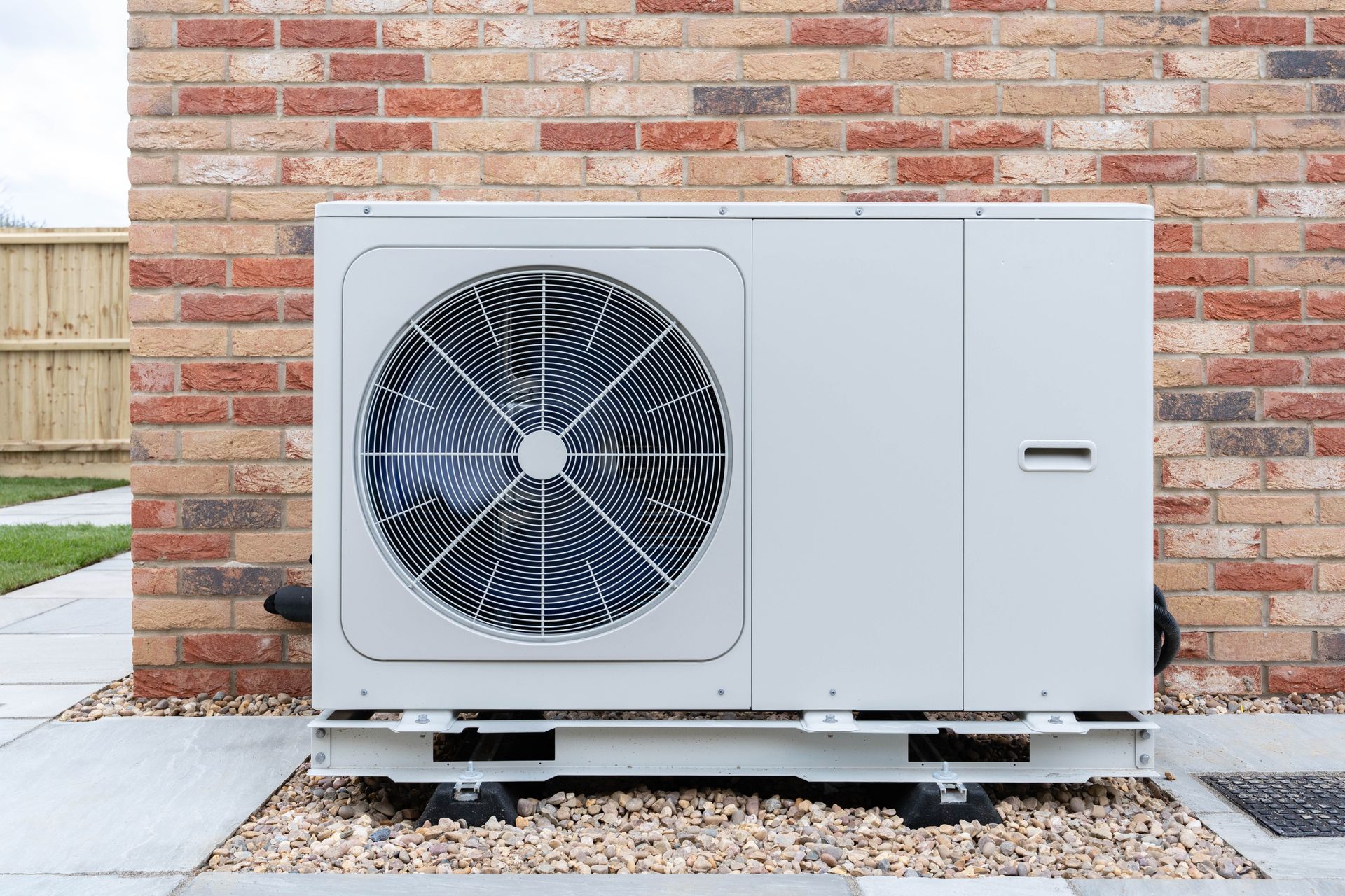 A white air conditioner is sitting outside of a brick building.