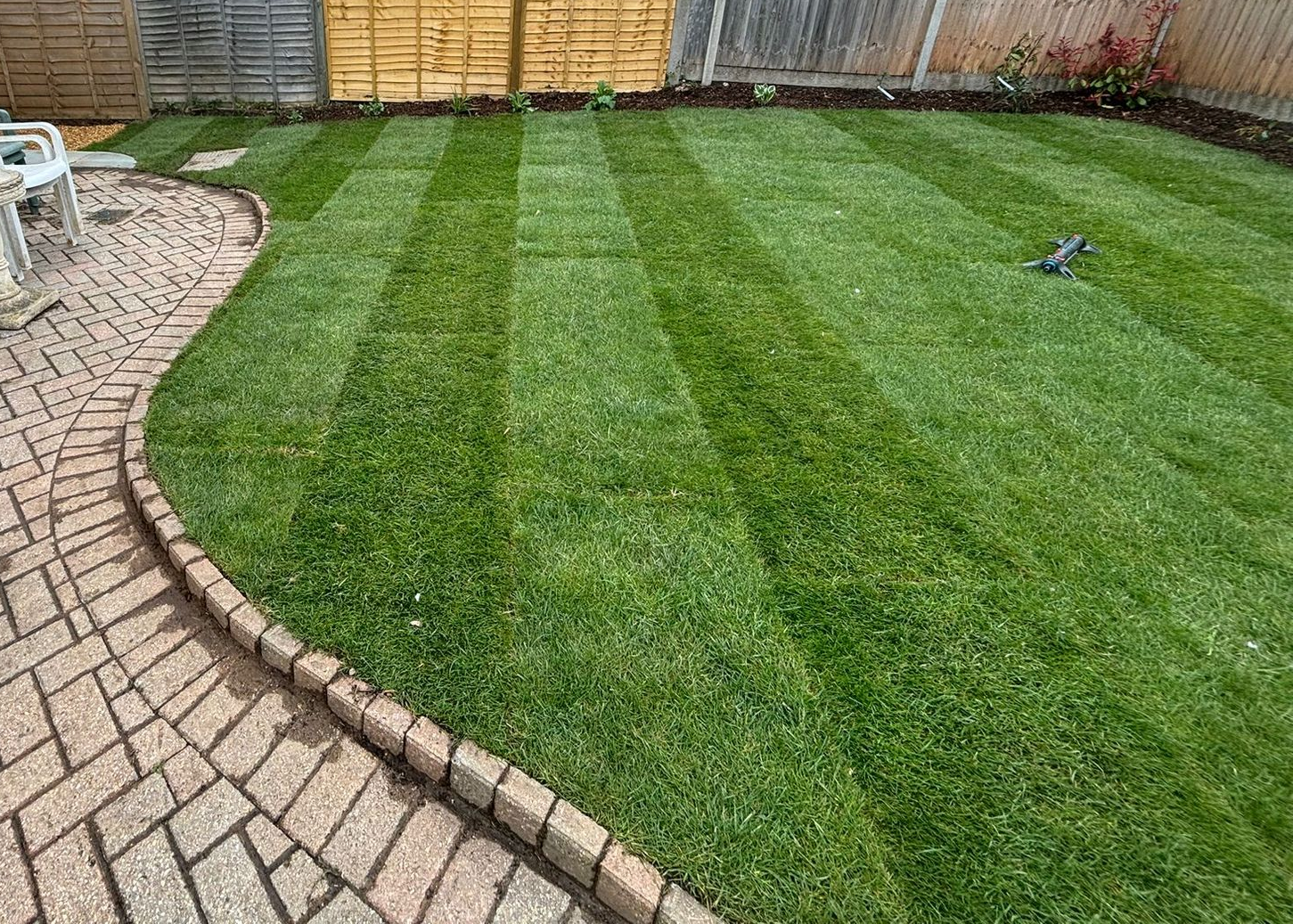 Freshly laid turf with winding path to the left and fecne to the rear