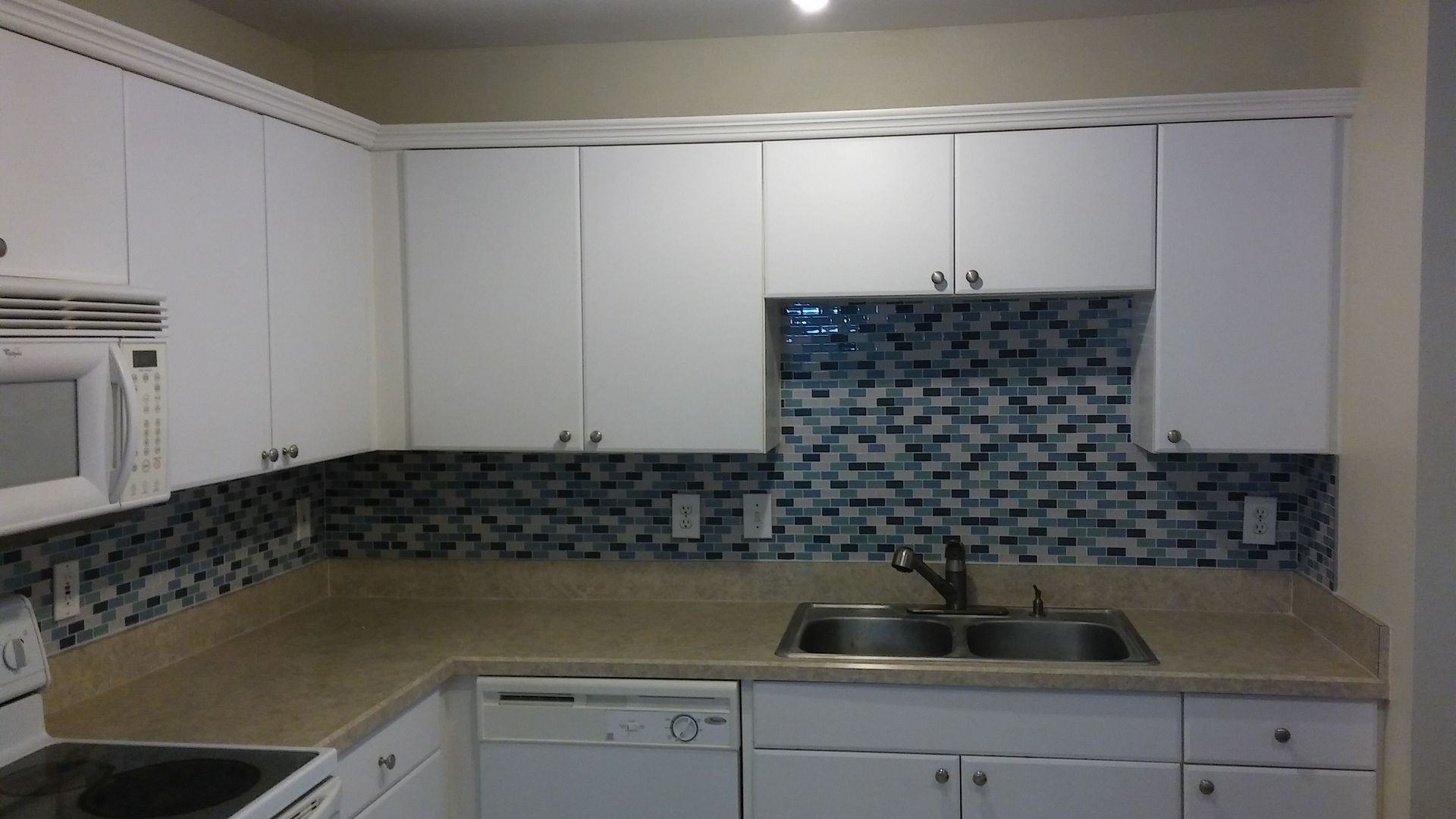 Person wearing gloves tiling white subway tiles on a wall, using spacers.