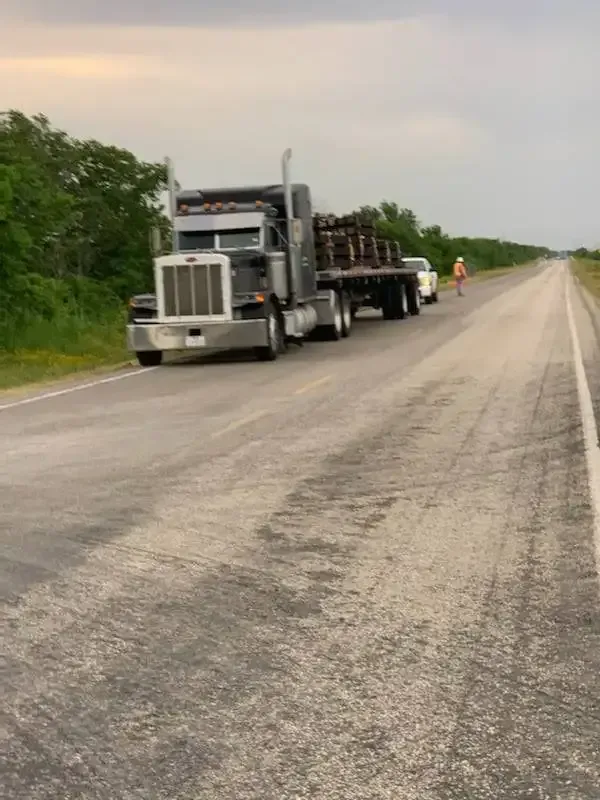 A semi truck with a flatbed trailer is driving down a highway.