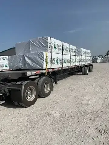 A semi truck is carrying a load of bricks on a dirt road.