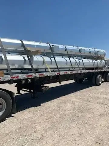 A semi truck is carrying a lot of pipes on a flatbed trailer.