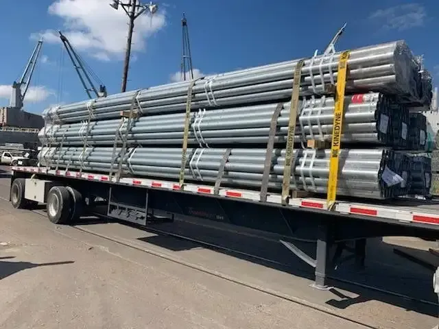 A semi truck is carrying a stack of metal pipes.
