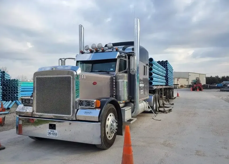 A large semi truck is parked in a dirt lot.