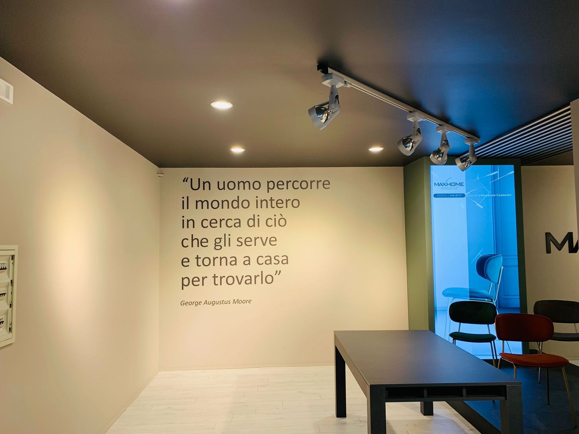 A room with a table, chairs, and a quote in Italian on the wall: 