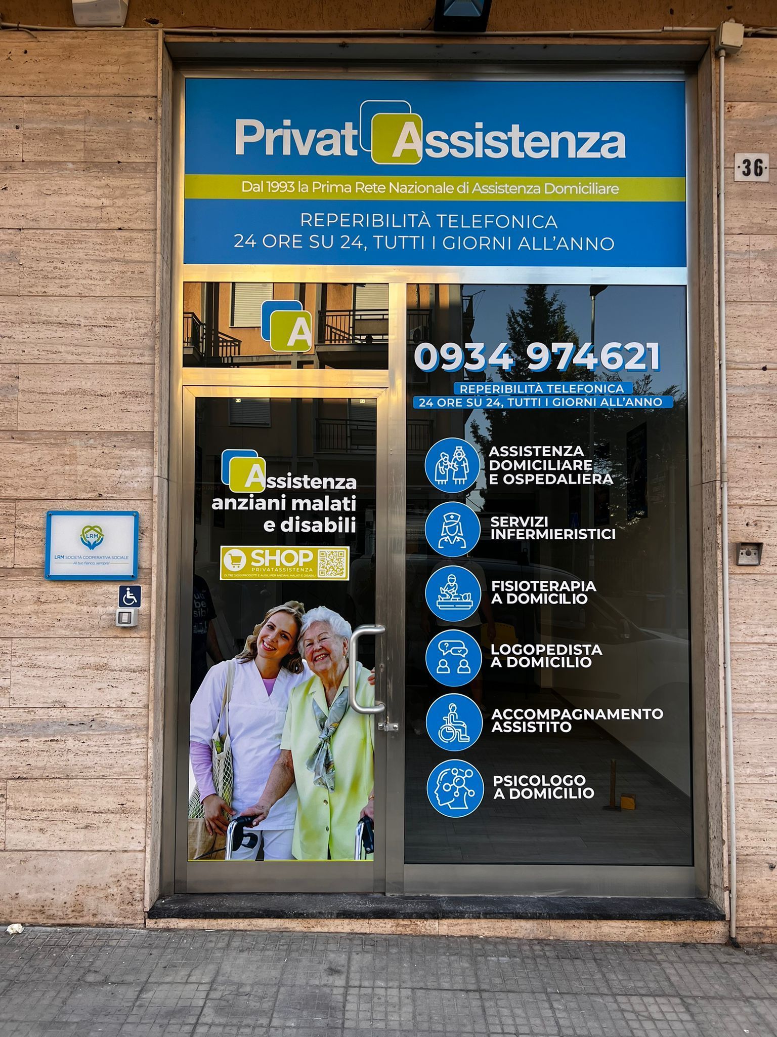 La vetrina di un centro PrivatAssistenza con le informazioni di contatto e un elenco grafico dei servizi sanitari offerti.