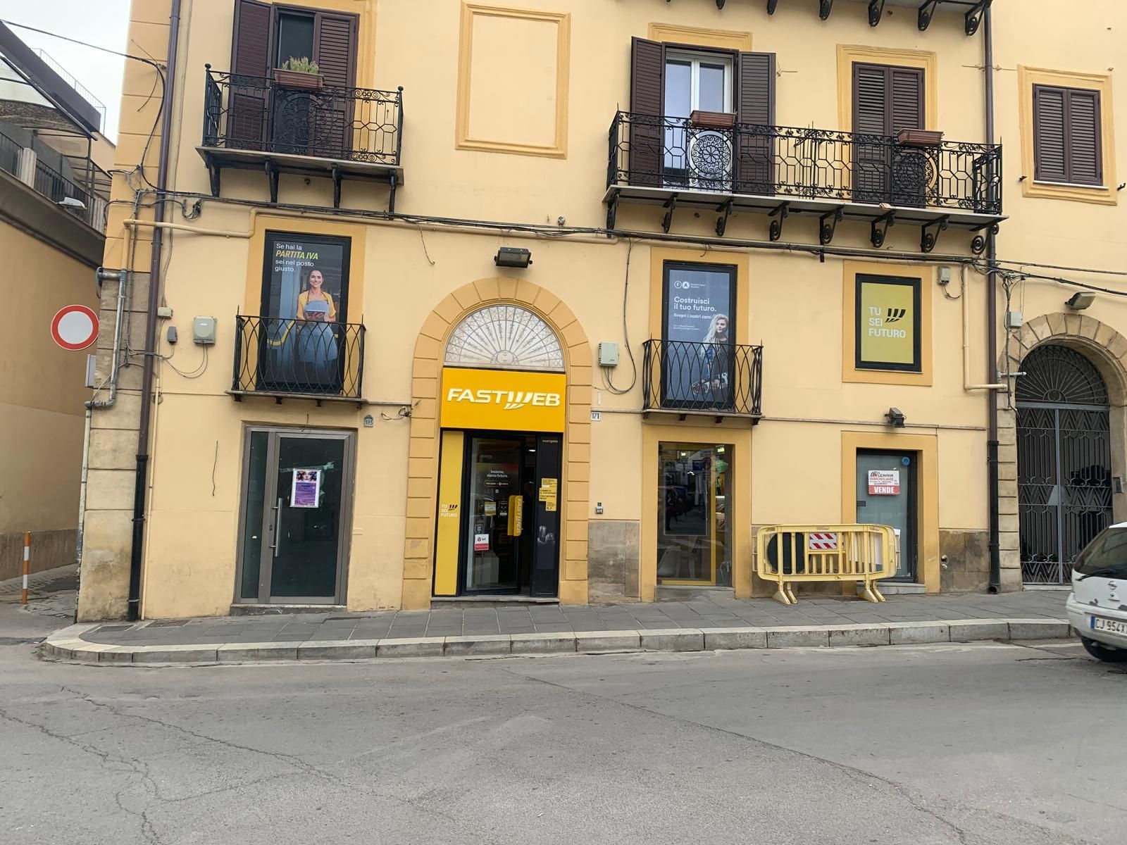 Vista a livello stradale di un edificio color crema con facciata gialla, su cui spicca l'insegna gialla 