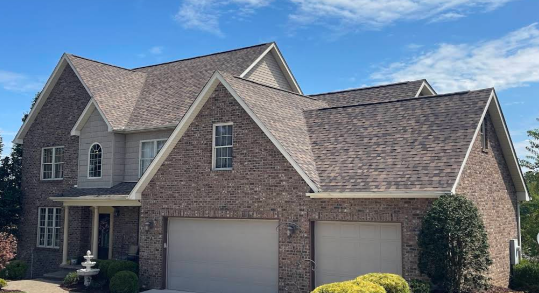 A large brick house with two garage doors and a gray roof.