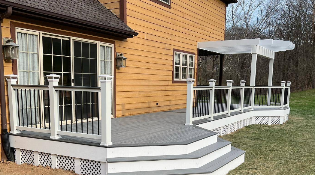 A yellow house with a large deck and stairs in front of it.