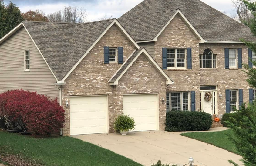 A large brick house with white garage doors and blue shutters