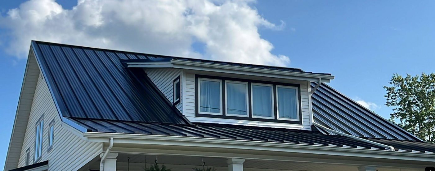 A white house with a black roof and a window on the roof.