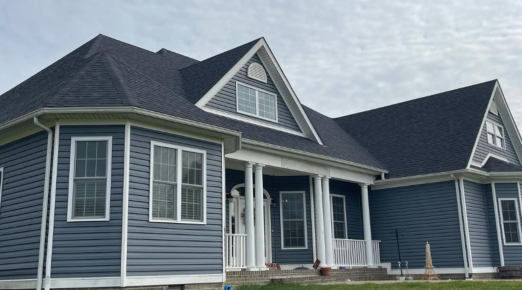 A large blue house with a black roof and white trim.