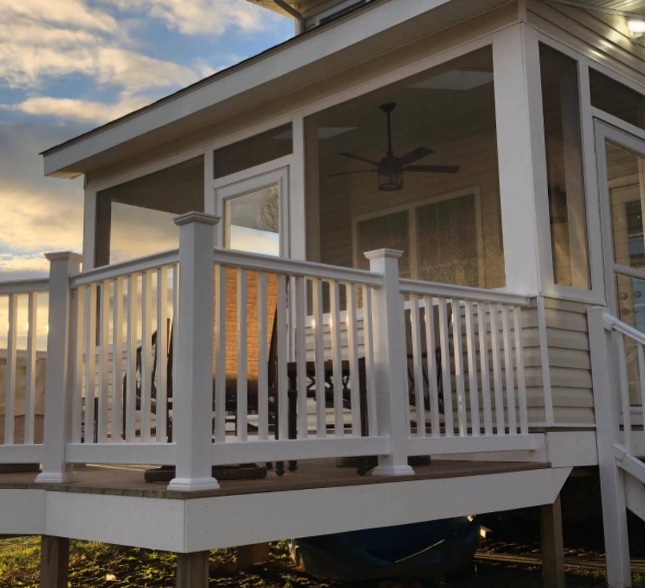 A white house with a screened in porch and a white railing