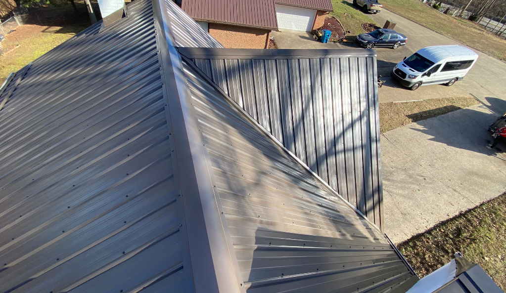 An aerial view of a metal roof with cars parked in front of it.