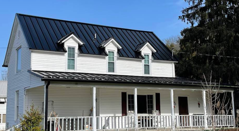A white house with a black roof and a porch.