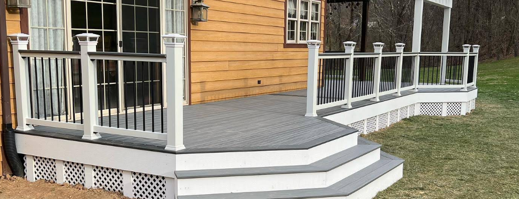 A porch with stairs and a white railing on a house.