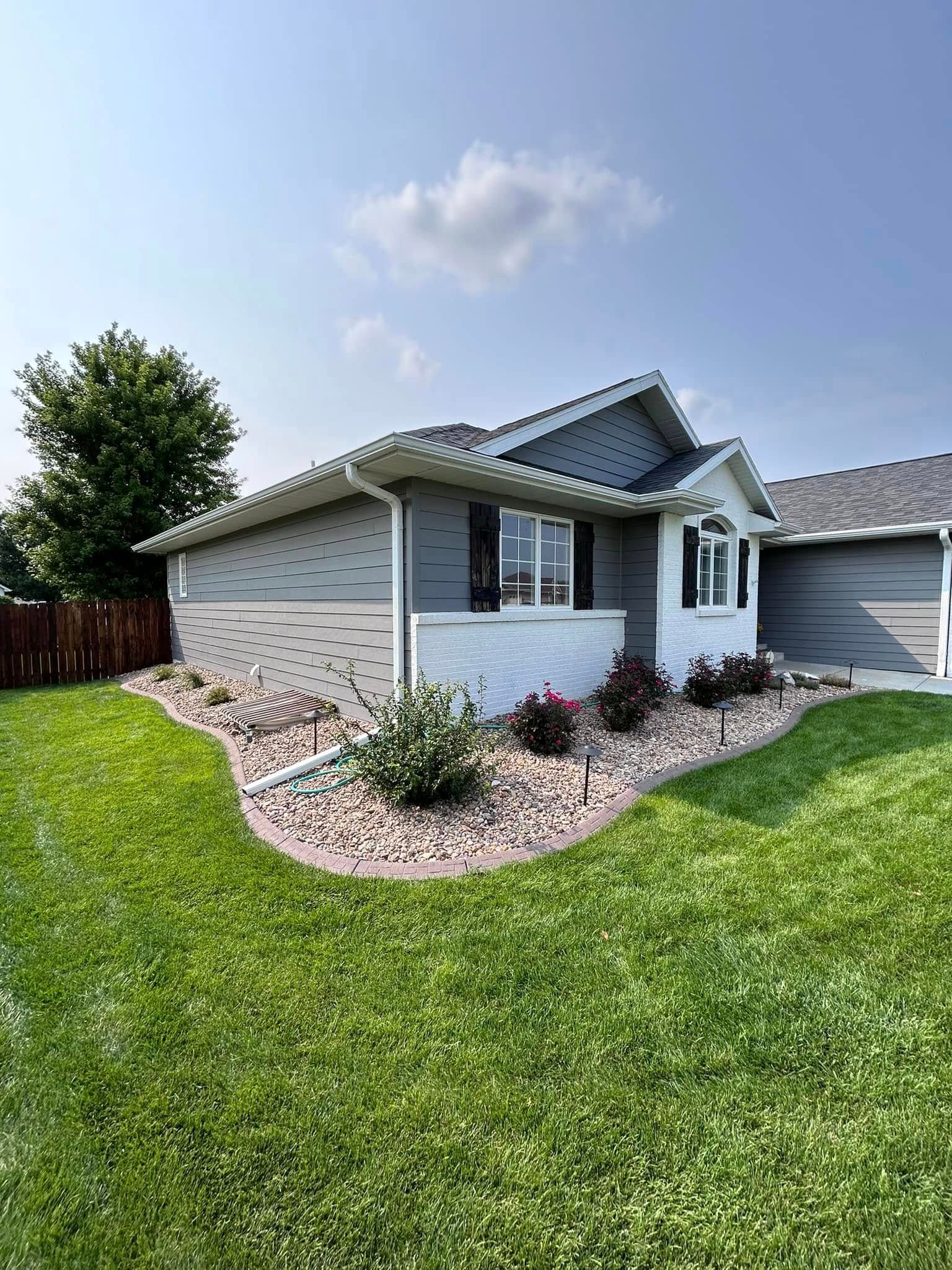Gray and white house with a landscaped front yard and blue sky.