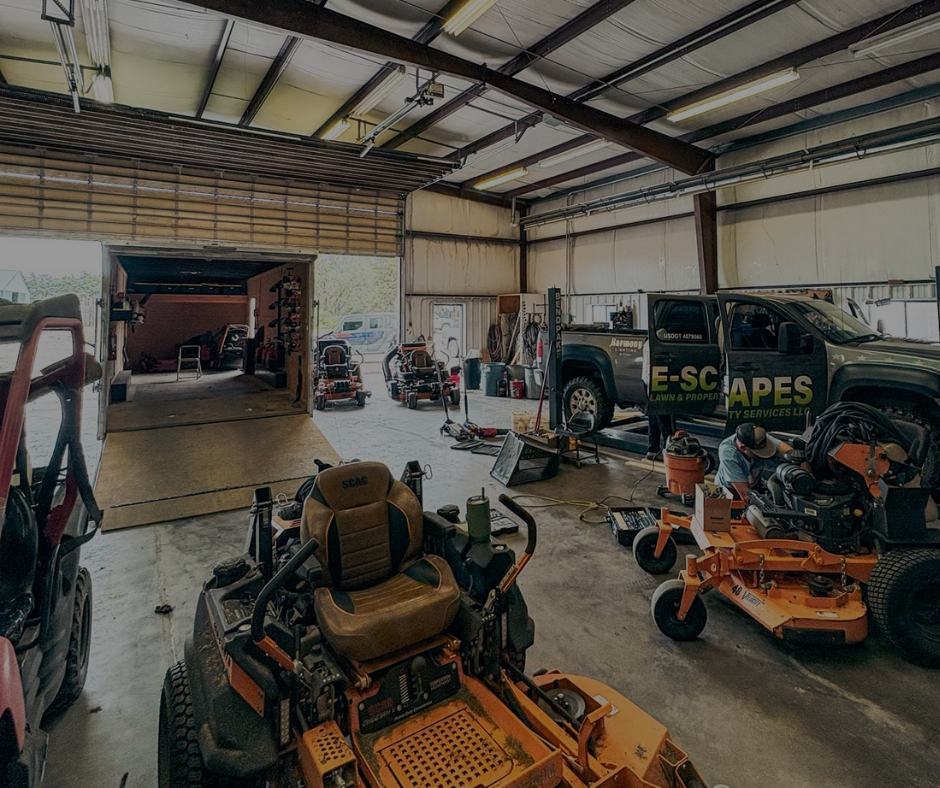 A large, open garage with lawnmowers, a truck, and equipment for landscaping.