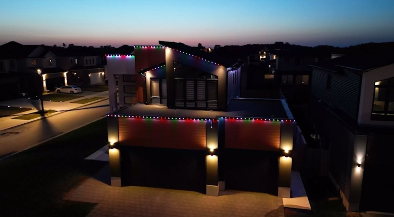 Modern house lit up at dusk with colorful string lights.