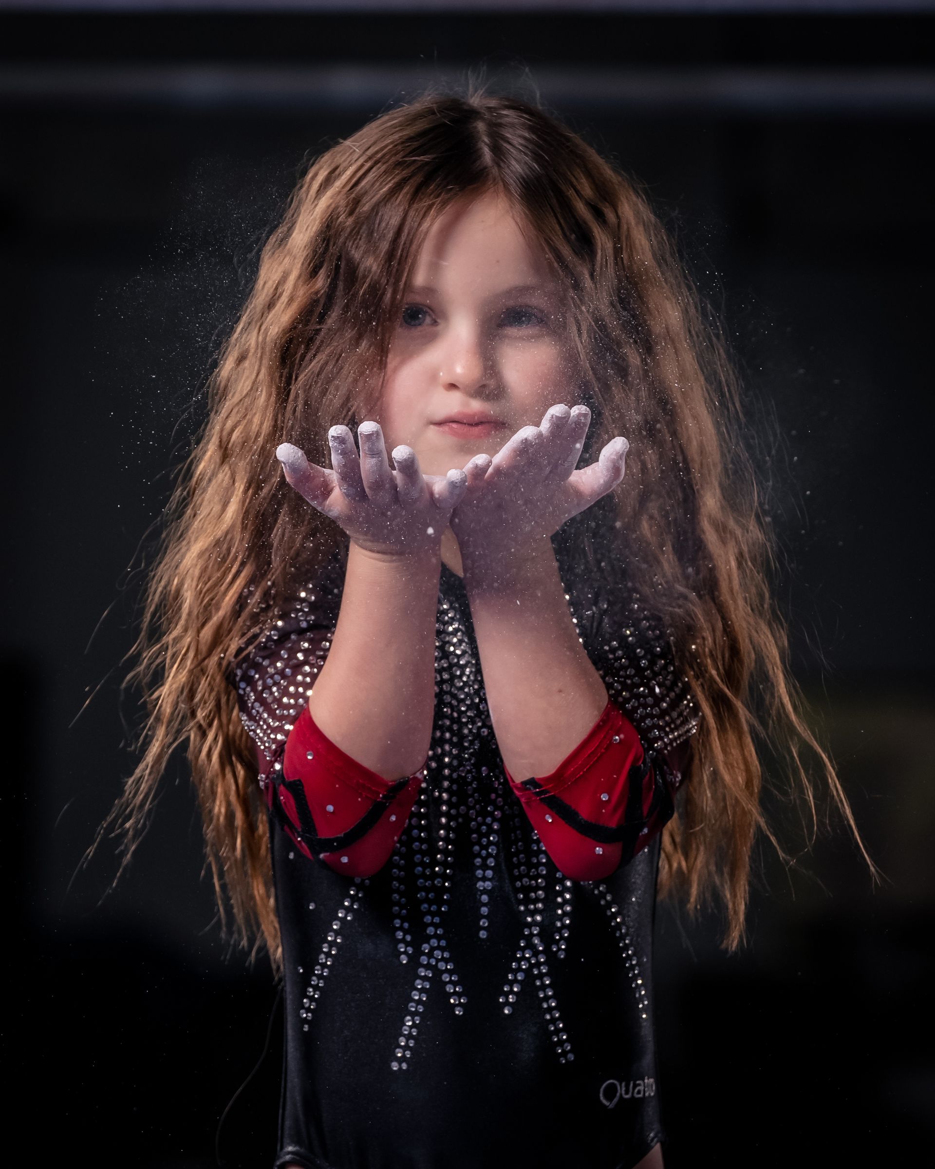 A little girl is holding chalk in her hands.