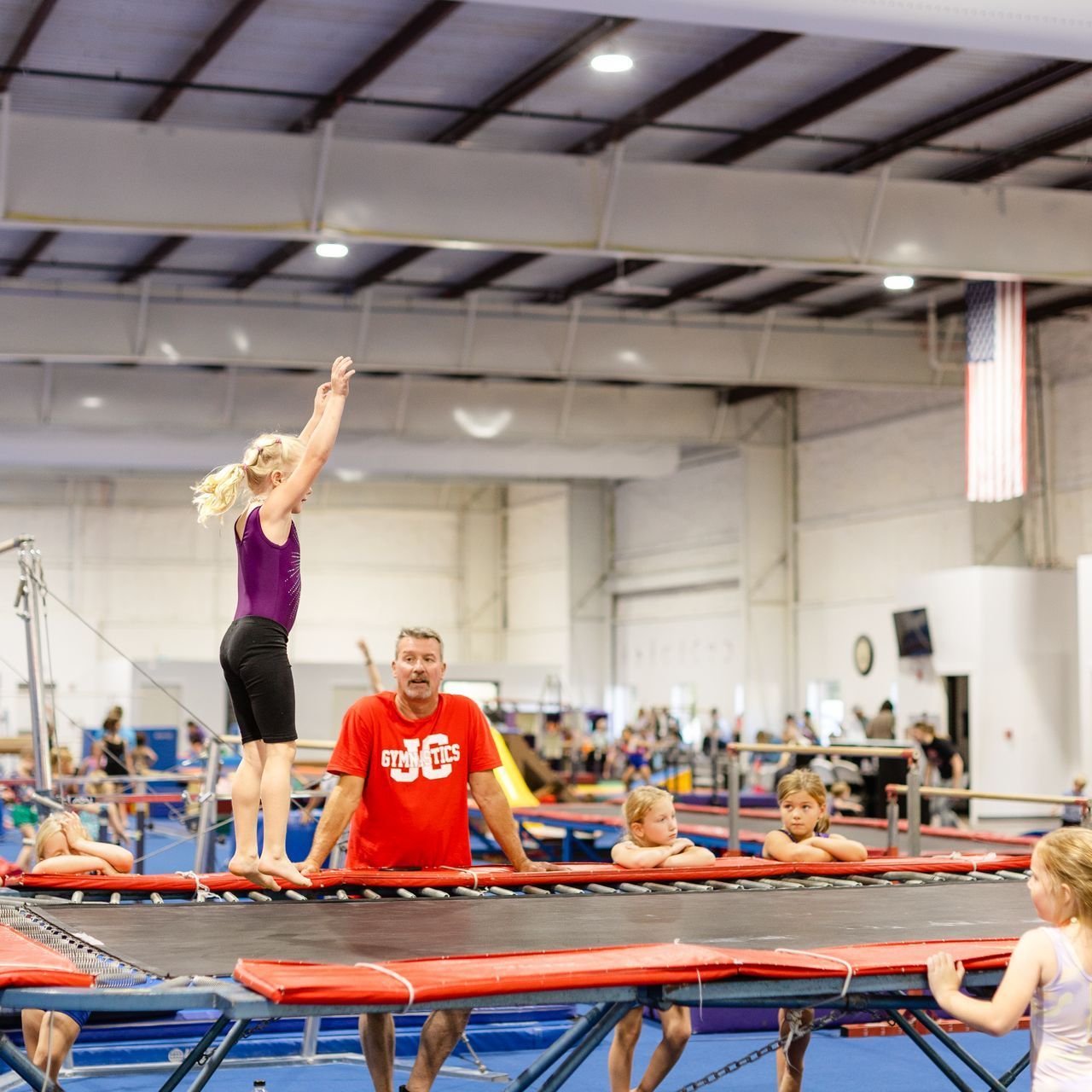 A group of people are playing on a trampoline in a gym.