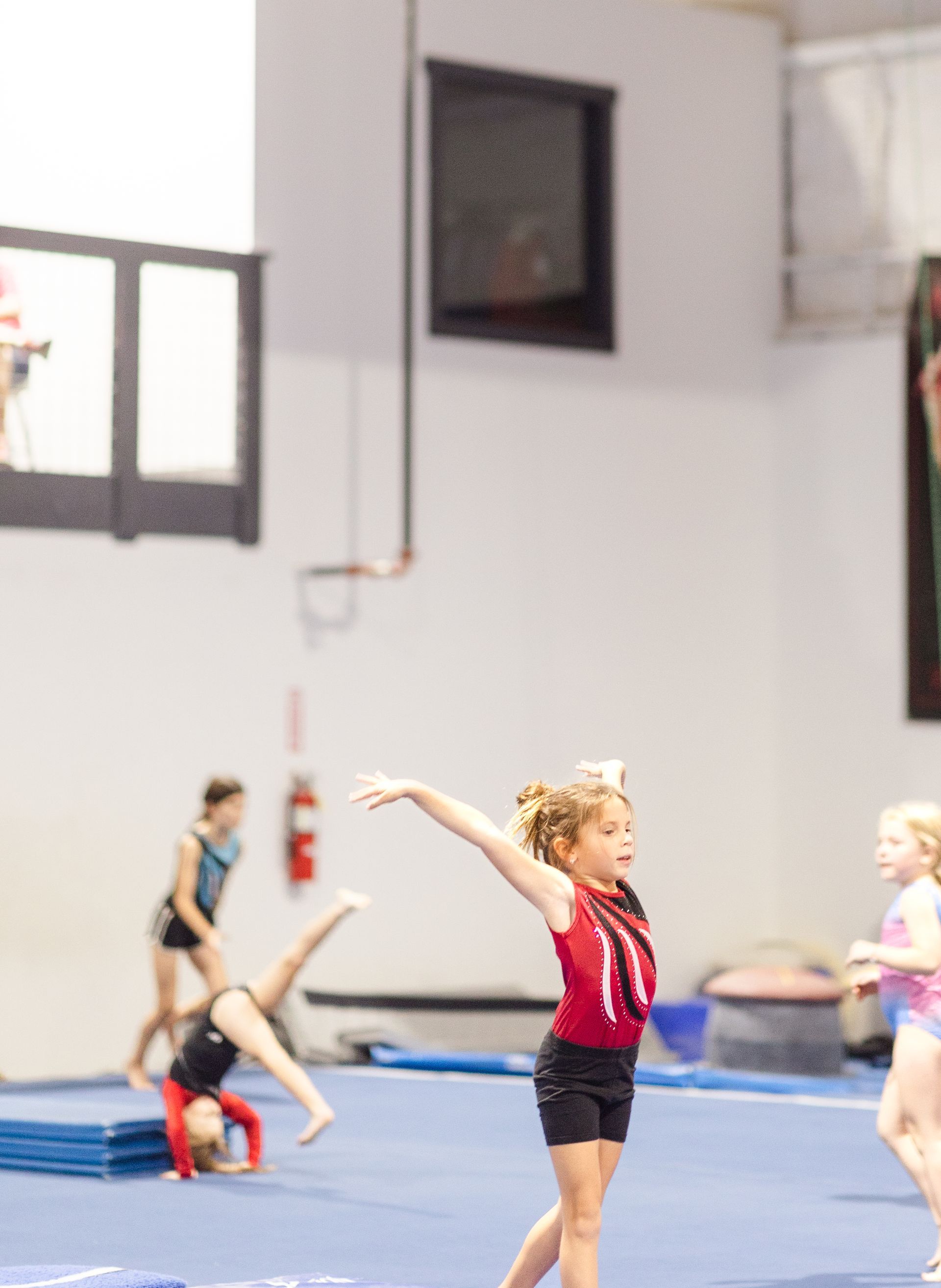A group of young girls are practicing gymnastics in a gym.