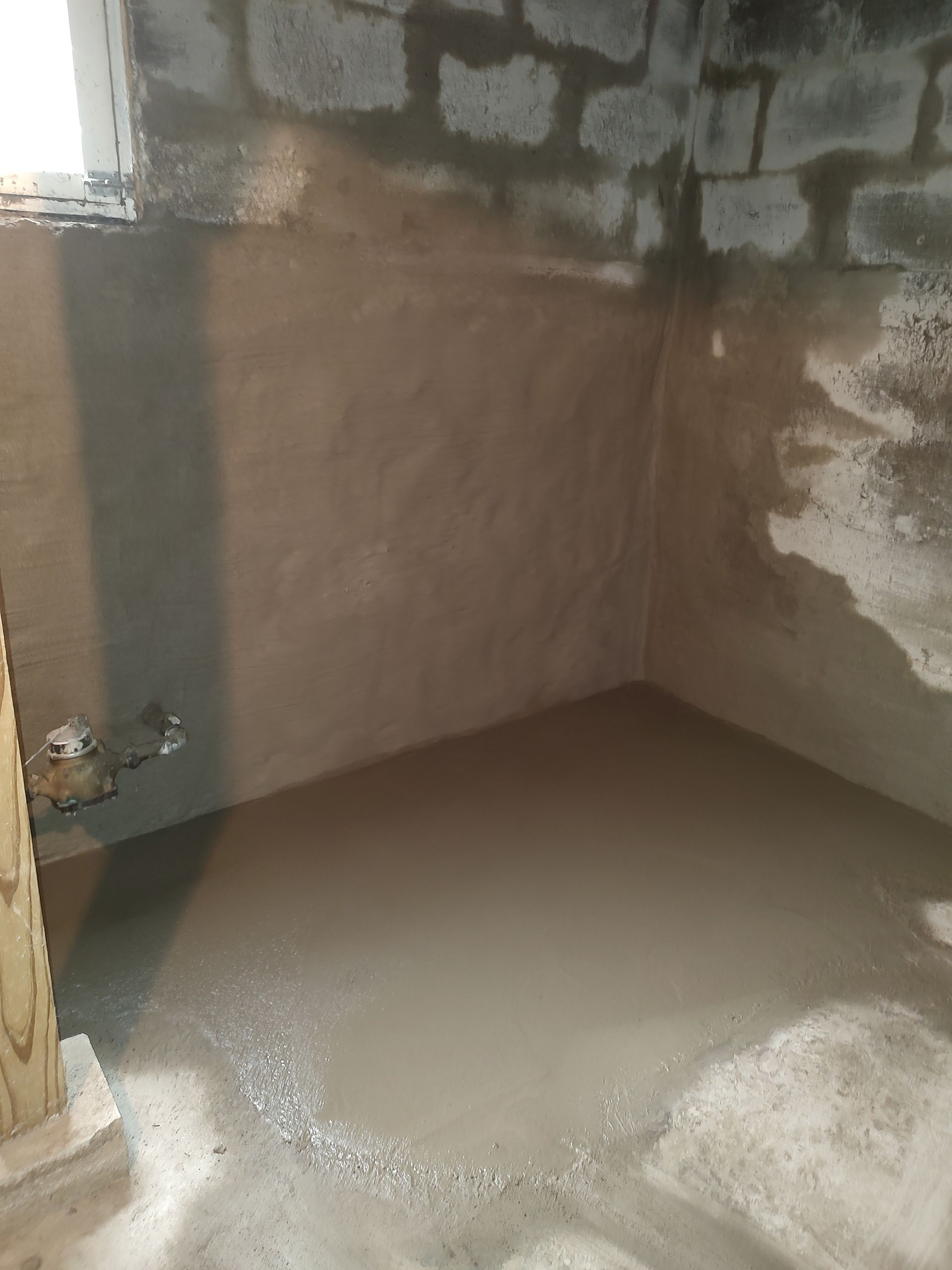 A room with a concrete floor and a brick wall.