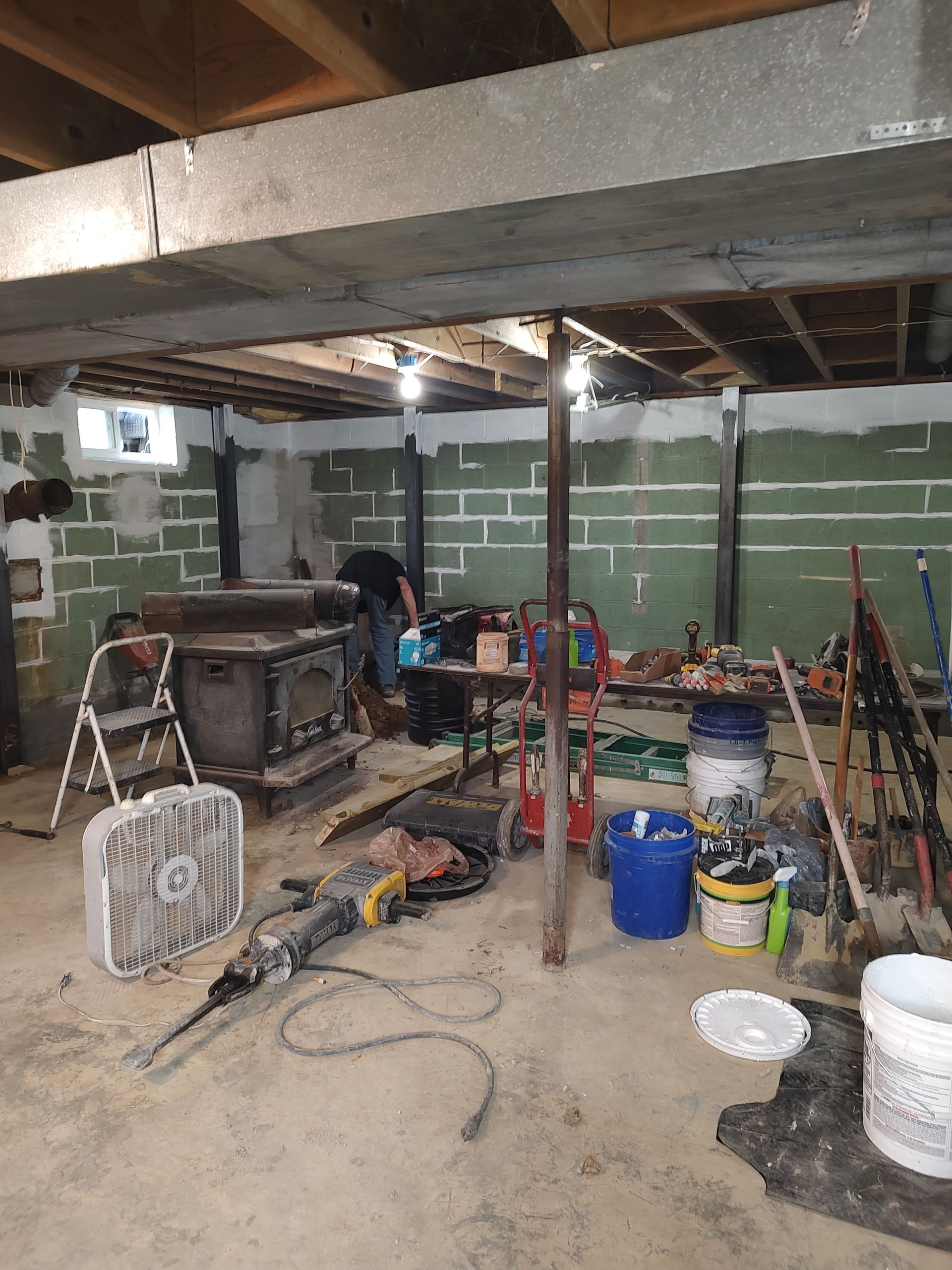 A basement with a lot of tools and a fan on the floor.