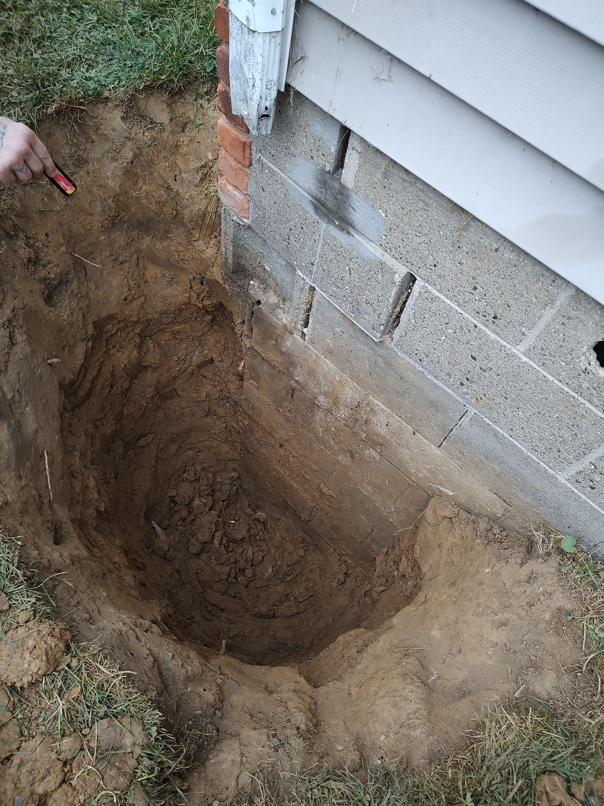 A person is digging a hole in the ground next to a house.