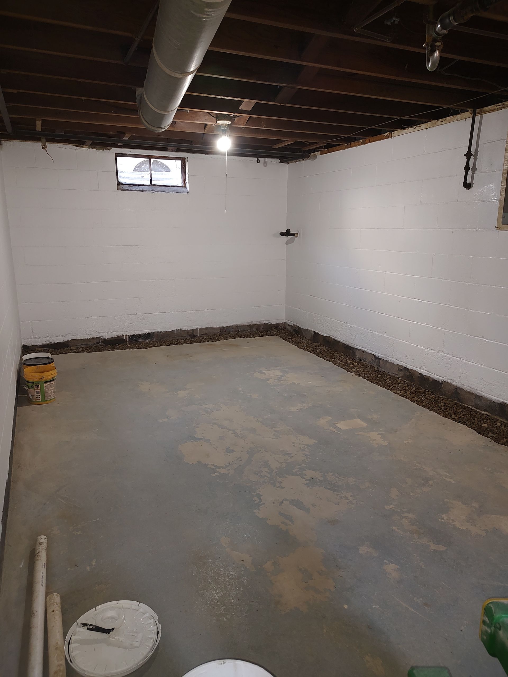 An empty basement with white walls and a concrete floor.