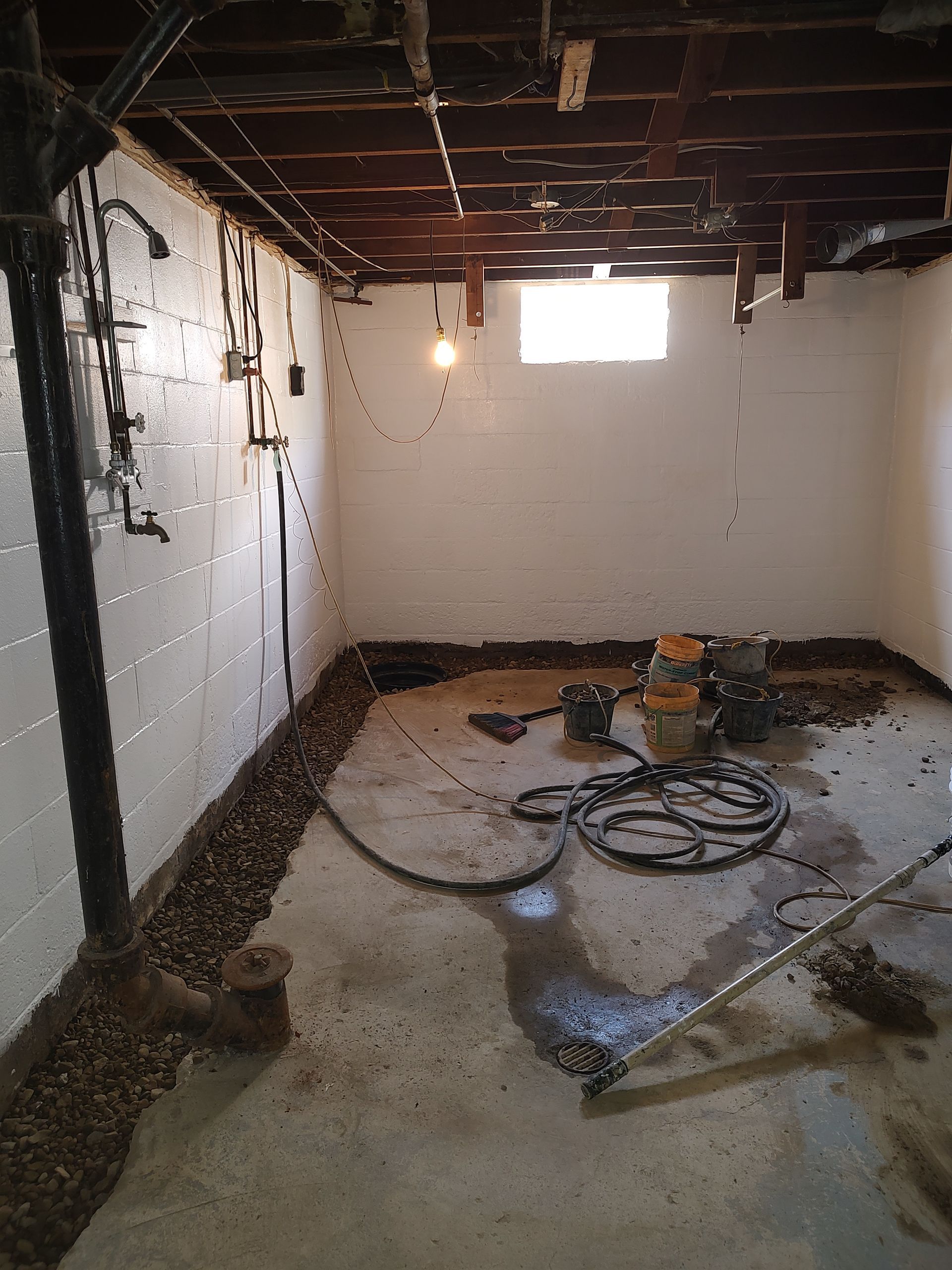 A basement with a lot of pipes and a window.